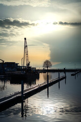 Fototapeta na wymiar Port au coucher du soleil avec une grue sur un barge de travail