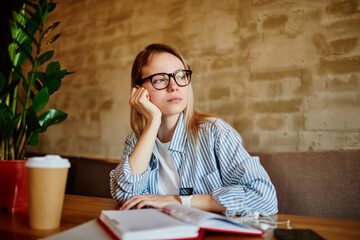 Serious woman contemplating and working in cafeteria