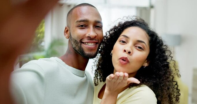 Selfie, happy and portrait of a couple in the living room of their new modern home together. Happiness, smile and young woman blowing a kiss while taking a picture with her husband in their house.