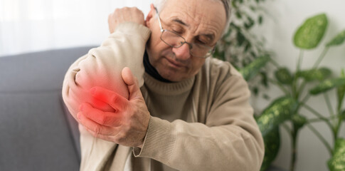 Guy holding hand to shoulder of aches, with red spot indicating location.