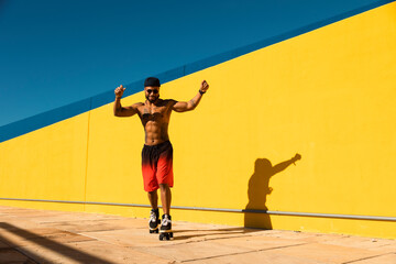 Black man on roller skates riding outside. Urban man posing with roller skates