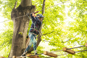 adventure climbing high wire park - children on course rope park. Portrait of cute little girl walk on a rope bridge in rope park