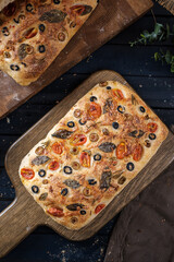Focaccia with olive tomatoes and rosemary. Homemade Italian Sourdough Bread on white cafe table. - 586946367