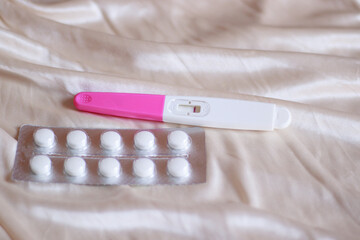 Contraceptive pills and a negative pregnancy test kit showing women's health, universal healthcare...