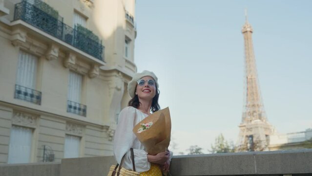 Smiling girl with a bouquet on the balcony overlooking the Eiffel Tower