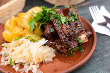 Bavarian pork ribs baked with sauce with boiled potatoes and sauerkraut