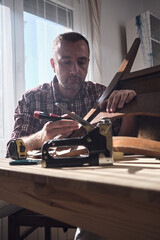Man working in a small home workshop for furniture repairing and restoration.