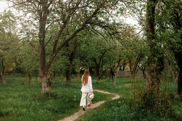 A beautiful young woman with long fair hair in light clothes in the fruit garden