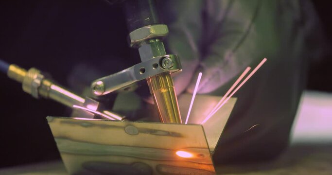 Laser welding machine with hand hold gun. Laser welding is shown in close-up.
