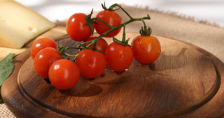 cherry tomatoes on a wooden cutting board. fresh vegetables before slicing. red tomatoes with water drops. close up.