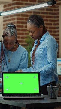Vertical video: Workers having laptop with greenscreen, using blank mockup display to review annual data statistics in office. Colleagues team checking reports, working with isolated chroma key screen
