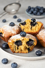 Homemade muffins with blueberry and almonds sprinkled with powdered sugar on plate on gray plate, Close up