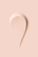 The texture of a smear of a light foundation on a beige background.