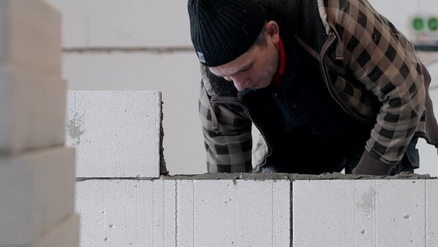 The builder places the block during the construction of the wall