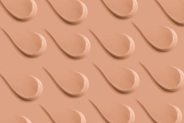 Many identical strokes of foundation on a beige background. Dark color.