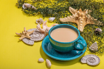 Obraz na płótnie Canvas A cup of coffee in a marine style. Starfish, shells, palm leaves. Hard light, dark shadow