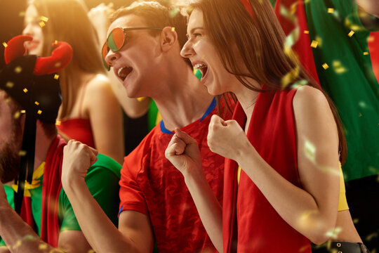 Portugal football fans supporting, watching match, emotionally cheering up favourite football, soccer team at stadium during game. Concept of sport, competition, championship, emotions, entertainment