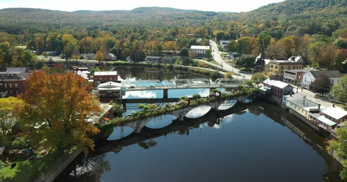 The Bridge of Flowers spans the Deerfield River with the rolling hills of Western Massachusetts as a backdrop in Shelburne Falls, MA during fall.