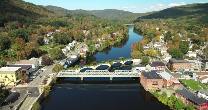 The Bridge of Flowers spans the Deerfield River with the rolling hills of Western Massachusetts as a backdrop in Shelburne Falls, MA during fall.
