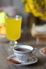 Cup of tea, plates with cookies, glass of orange juice, books, reading glasses, bowl of fruit and candles on the table. Selective focus.