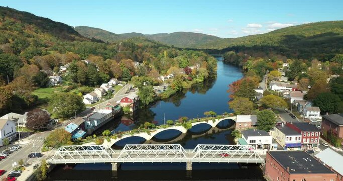 The Bridge of Flowers spans the Deerfield River with the rolling hills of Western Massachusetts as a backdrop in Shelburne Falls, MA during fall.