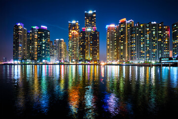 Busan Marina city skyscrapers illuminated in night with reflection in water, South Korea