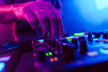 Close up of DJ hands on dj console mixer during concert in the club