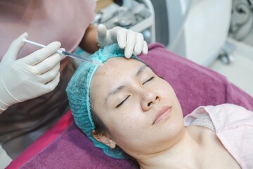 Obraz na płótnie Canvas A nurse injects a skin serum onto the face of an Asian woman. In beauty clinics, Medical and cosmetic dermatology appointments concept.