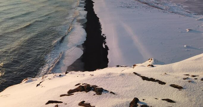 View at sunset of Kirkjufjara black sand beach from the Dyrholaey Promontory during winter in the south of Iceland.