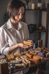 Female soap maker holds a piece of handmade soap. A lot of different sliced pieces. Eco-friendly natural craft cosmetics
