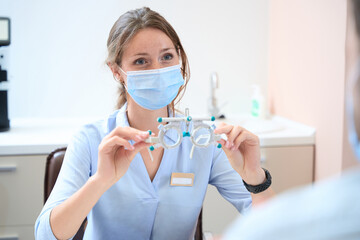 Caucasian optometrist in uniform with professional equipments in the clinic