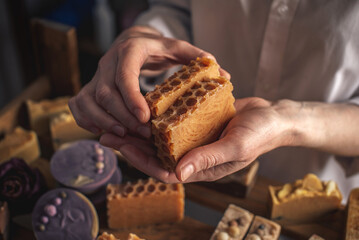 Female soap maker holds a handmade honey soap in her hands. A lot of different sliced pieces. Eco-friendly natural craft cosmetics