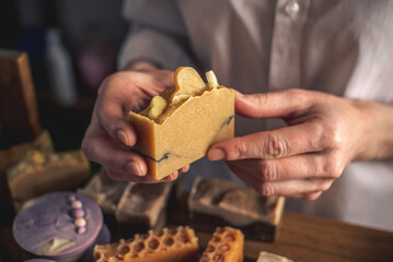 Female soap maker holds a handmade orange soap in her hands. A lot of different sliced pieces. Eco-friendly natural craft cosmetics