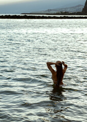 Freedom. Photo of a girl relaxing and swimming in the ocean water after the sunset. Wanderlust
