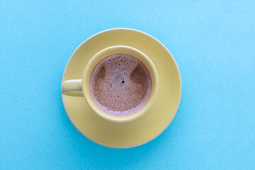 Yellow cup of coffee on blue background. Top view. Coffee concept.