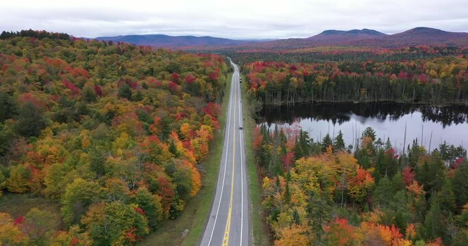 State Highway 3 slices through the colorful autumn landscape past Panther Pond near Panther Mountain Bog in Adirondack Park in Upstate New York.