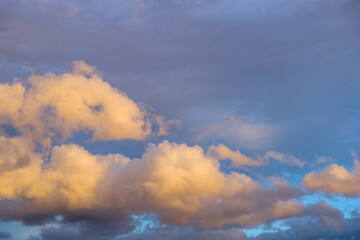 Fototapeta na wymiar Clouds in golden light with the rain cloud in background