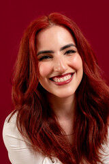 Confident woman looking at the camera and smiling while posing against a red isolated background.