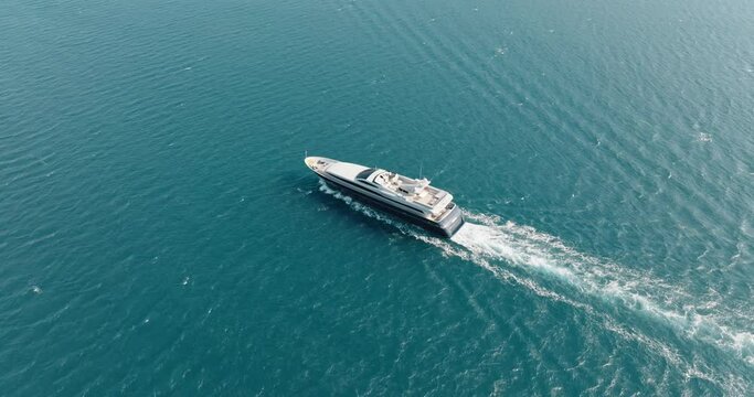 White luxury motor yacht sailing with water scooter blue sea surface with small waves in sea aerial view drone. Tourists strolling boat. White path on water boat. 