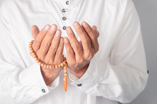 Hand of a Muslim man holding tasbih beads