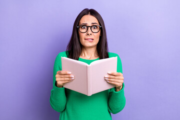 Fototapeta premium Photo of shocked funny woman wear green pullover spectacles reading scary book isolated purple color background