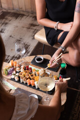 Obraz na płótnie Canvas Mujeres y manos femeninas comiendo sushi en un restaurant con vajill rustica