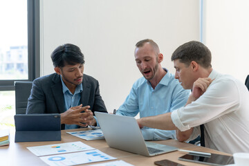 Fototapeta premium Group of diverse businessman going over paperwork together and working on laptop at meeting.
