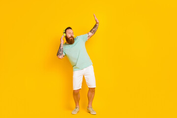 Fototapeta na wymiar Full body photo of carefree guy dancing have fun listen wireless headphones chilling high quality jazz music isolated on yellow color background