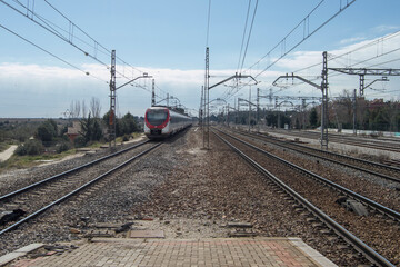 train tracks and power lines with a train in the background of a railway line in Spain