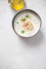 Cream-soup made of cauliflower cabbage on a light-beige stone background, above view, vertical shot, copy space