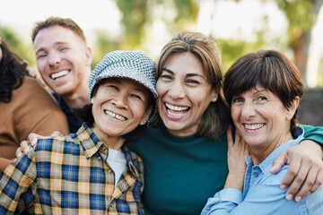 Happy multiracial senior women hugging each other outdoor - Group of multigenerational people having fun at city park