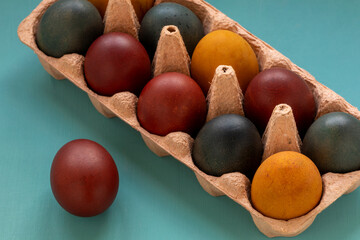 Colorful eggs in egg storage box. Eggs colored in organic dyes (onion skin, turmeric, red cabbage).