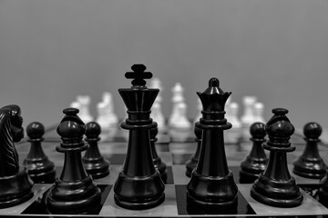 Black chess pieces background white blurred chess pieces standing chessboard.