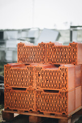 A pile of bricks has been stacked neatly on a wooden pallet at a construction site, ready for use in building projects.